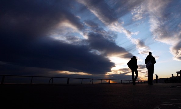 Silhouette of two people walking at sunset